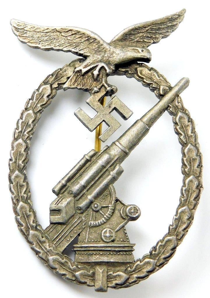 Luftwaffe Flak Artillery Badge: Two-piece die-struck nickel construction. Front shows an 88 flak artillery gun in the center. Luftwaffe flying eagle clutching a swastika in its talons at the top. Both are surrounded by an oval oak l