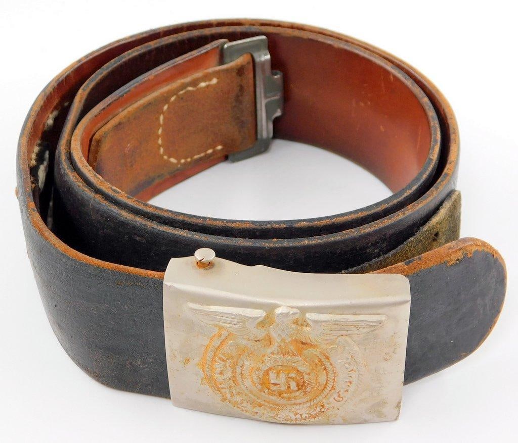 Waffen SS Schutz Staffel EM Belt and Buckle: Die-struck stamped steel construction. For an enlisted man. Belt buckle measures 2 1/2 inches wide by 1 7/8 inches tall. Front shows a Waffen SS eagle clutching a swastika in its talons in the center.