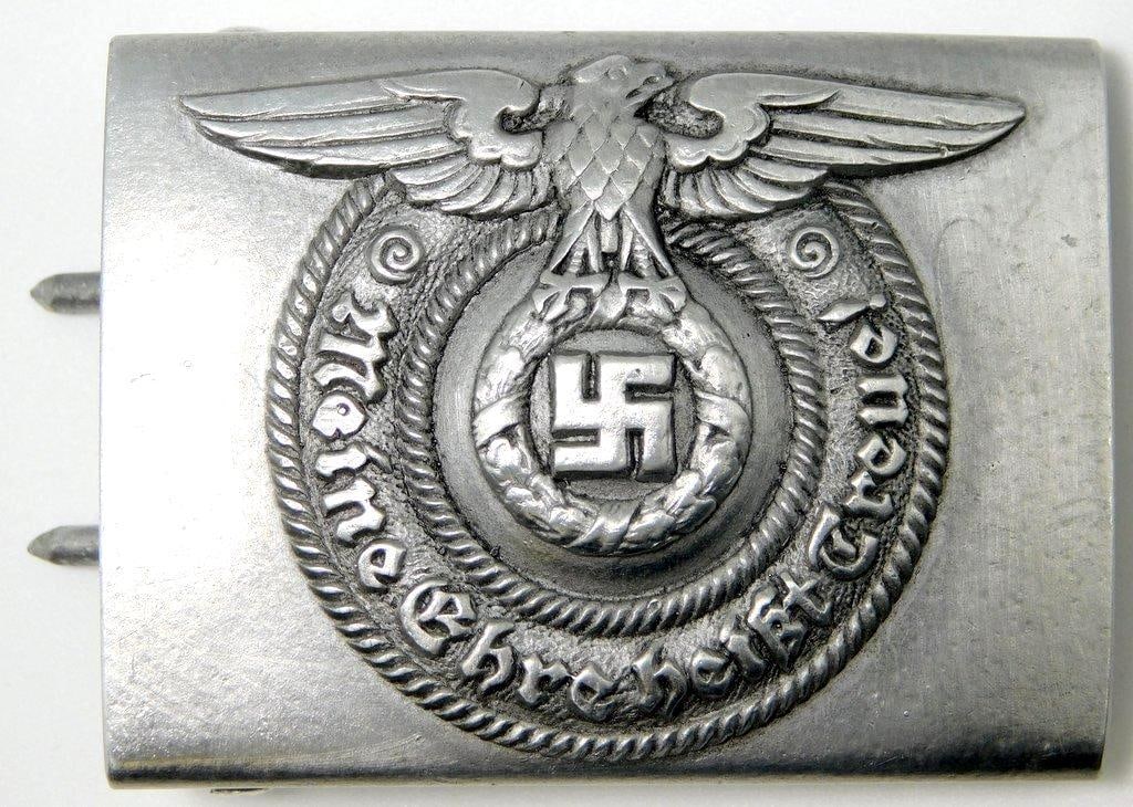 German WWII Waffen SS Schutz Staffel EM Belt Buckle: Aluminum construction. For an enlisted man. Front shows a Waffen SS eagle clutching a swastika. Reads Meine Ehre heist Treue! (My Honor is Loyalty!). Reverse is maker-marked RZM 36/39 SS. Includes bot