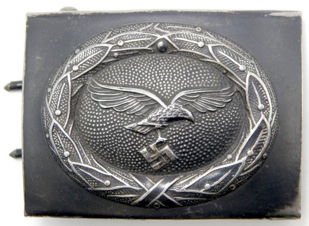 Luftwaffe EM Belt Buckle: One-piece die-struck stamped gray painted steel construction. For an enlisted man. Front shows a Luftwaffe flying eagle clutching a swastika. Both are surrounded by an oval oak leaf wreath. Reverse is