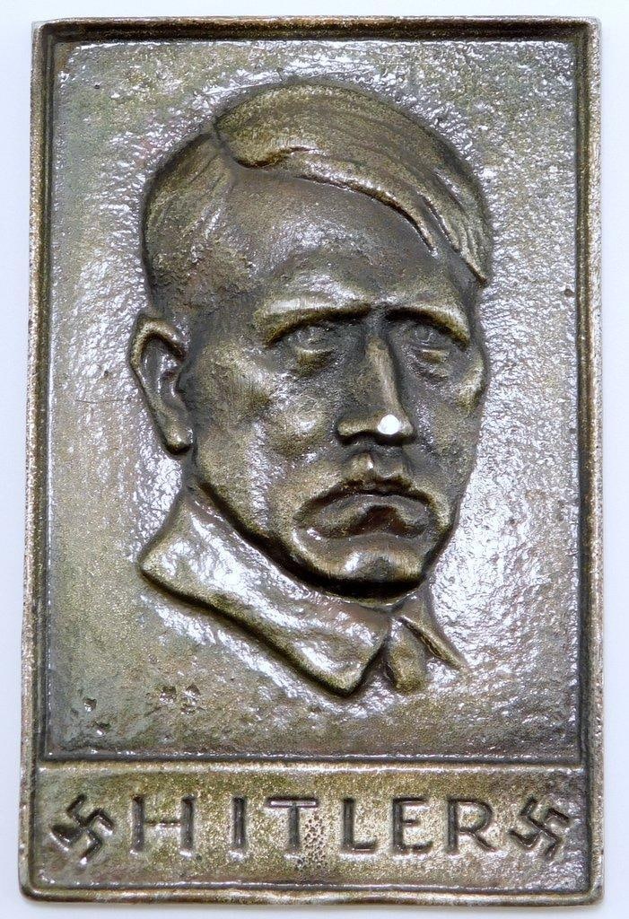 Dictator Adolf Hitler Plaque: Solid nickel construction. Front shows a bust image of Hitler. Reads Hitler with two swastikas at the base. Measures 3 1/4 inches wide by 5 inches tall.