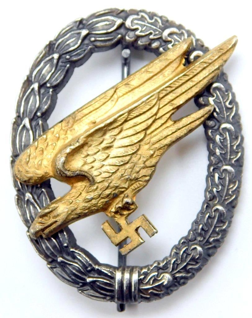 German WWII Luftwaffe Paratrooper Fallschirmjager Jump Badge: Two-piece die-struck two domed rivet nickel and brass construction. Front shows a diving eagle clutching a swastika in its talons. Both are surrounded by an oval oak leaf wreath. Reverse is maker-mark