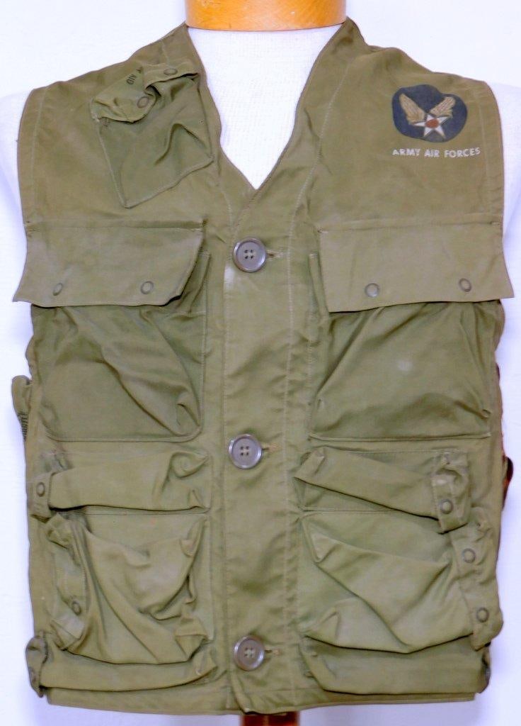 USAAF WWII Army Air Forces Combat Survival Vest: Multi-piece machine-sewn OD green nylon construction. Shows some use and wear. Printed Air Corps patch on the upper left-hand breast and reads ARMY AIR FORCES below. Pockets with snaps and leather hol