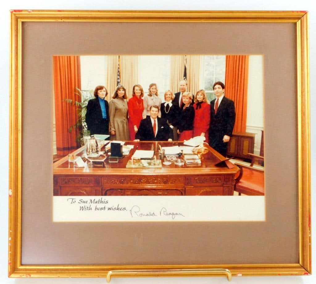 Framed Color Photograph Signed by U.S. President Ronald Reagan: Framed photograph depicting Ronald Reagan alongside a group of individuals in the Oval Office. The photo is personally inscribed, To Sue Mathis, With best wishes, and signed by President Ronald Reagan