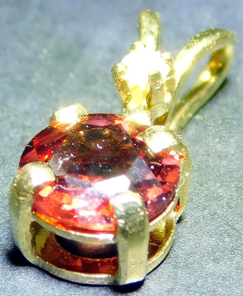14K Gold Pendant w/ Tourmaline Stone: 14K yellow gold pendant featuring a round-cut tourmaline tested gemstone set in a secure prong setting, paired with a smaller clear gemstone The piece is crafted with a looped gold bail for easy attac