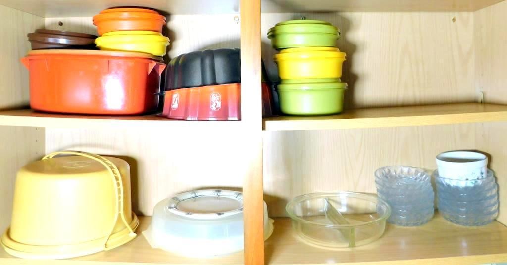 Plastic and Glass Kitchenware, Including Tupperware and Glass Bowls: Kitchenware comprising plastic Tupperware containers in various colors (orange, green, yellow, and brown), a yellow plastic bucket with a lid and handle, a selection of clear glass bowls with decorati
