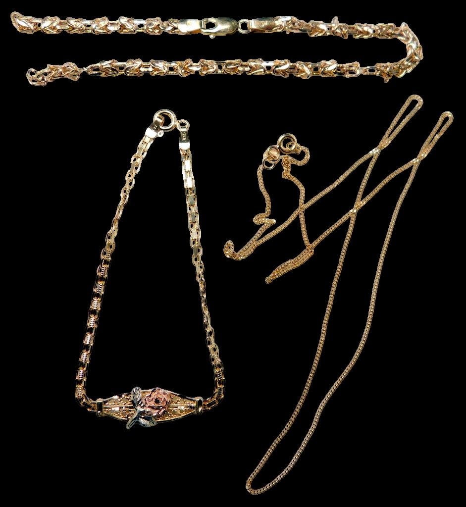 Gold Necklaces and Bracelet w/ Floral Design: Multiple gold jewelry pieces, including chain necklaces and bracelets Pieces include a bracelet with a rose floral motif and filigree details, a chain bracelet with interlinking design, and a fine