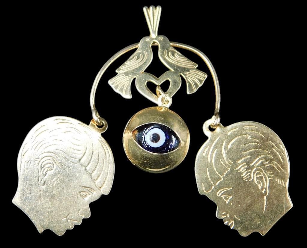 14K Gold Pendant w/ Engraved Profiles, Evil Eye, and Bird Motif: 14K gold pendant featuring a central evil eye motif, two engraved child profiles labeled as shown, and two kissing bird figures forming a heart above The design combines personalized engravings with s
