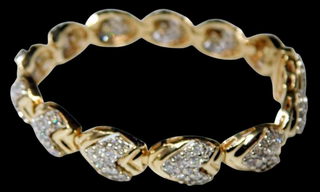14K Yellow Gold Bracelet w/ Diamond Accents: 14K yellow gold bracelet featuring a series of interlinked leaf-shaped segments, each adorned with round-cut diamond accents set in a pave style The bracelet is secured with a box clasp, marked 14K,