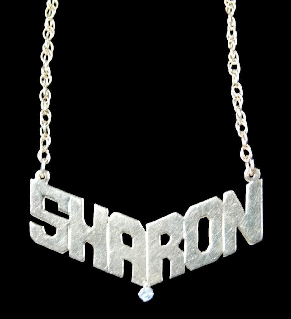 14K Gold Custom Pendant Necklace w/ 'Sharon' Design and Diamond Accent: A 14K gold pendant necklace featuring a bold, custom-cut design spelling SHARON The pendant includes a small round tested diamond accent suspended below the lettering Hallmarked 14K and ELKA on
