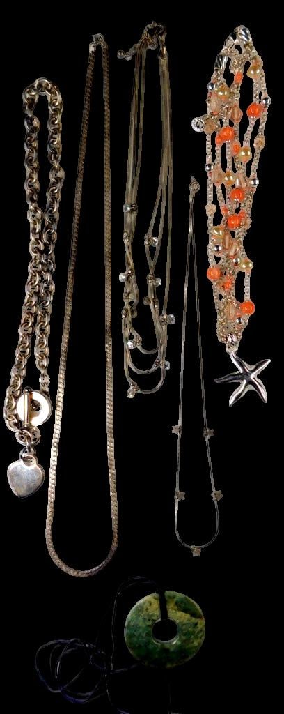 Necklaces Including Stone Pendant and Starfish Charm: A variety of necklaces in different materials and styles Highlights include a green circular stone pendant on a black cord, a silver-tone chain with a heart-shaped charm, a layered necklace adorned wi