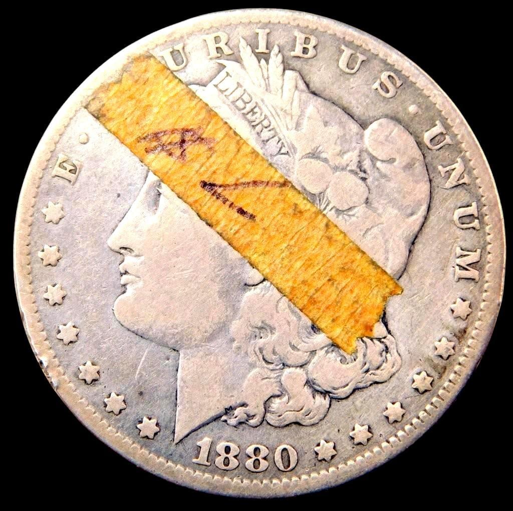 1880-O Morgan Silver Dollar Coin: 1880 Morgan Silver Dollar, New Orleans Mint Condition shows signs of wear, discoloration, and adhesive tape affecting the obverse side Features standard lettering and detail