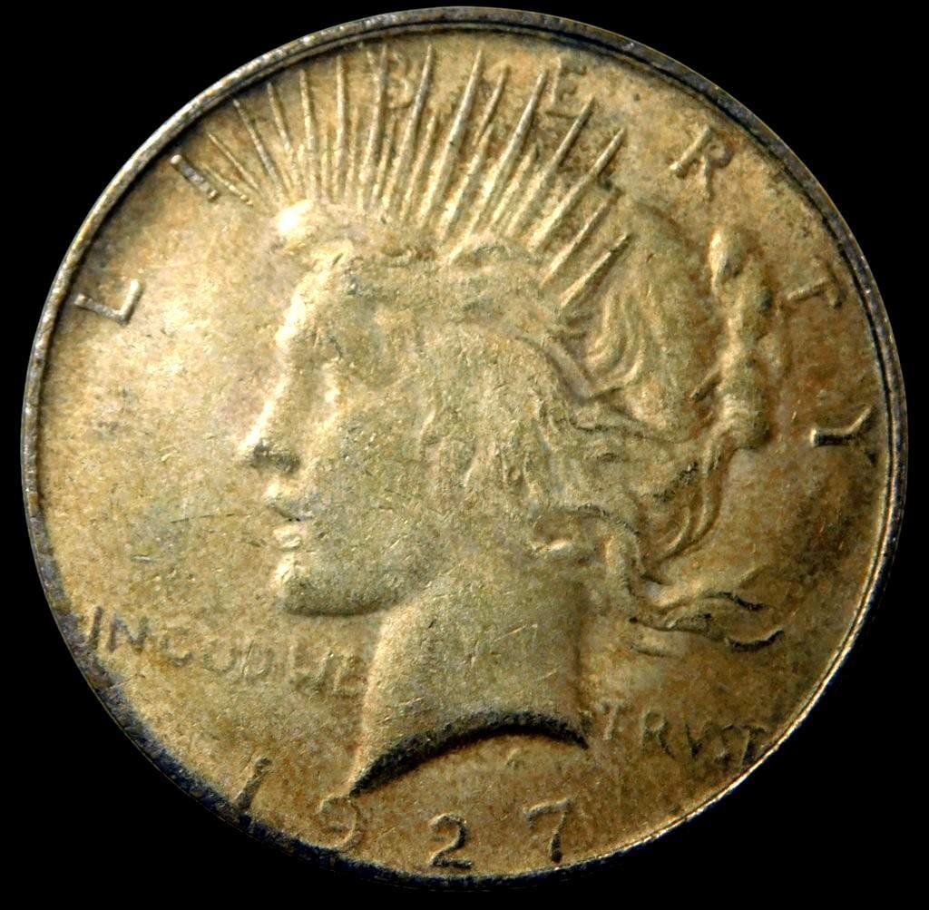 1927 Peace Silver Dollar Coin: 1927 Peace Silver Dollar, featuring Lady Liberty and an eagle design The coin shows signs of circulation, including wear on details and possible tarnishing Lower mintage coin