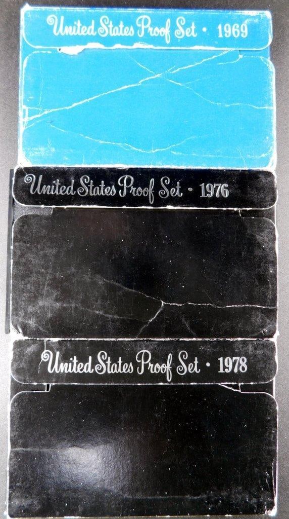 United States Proof Sets 1969, 1976, and 1978 in Original Packaging: Three United States Proof Sets from 1969, 1976, and 1978, each in their original government packaging The outer boxes show wear, such as creases, scratches, and some tearing, but the coins inside rema
