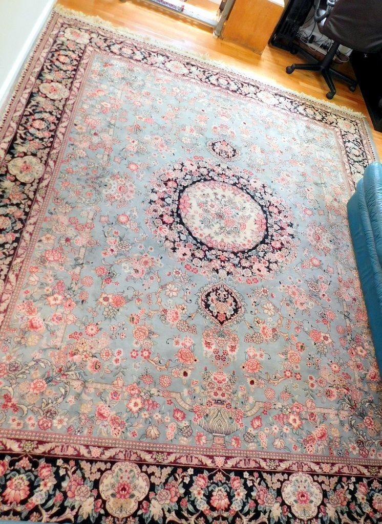 Persian-Style Area Rug w/ Floral Motif and Light Blue Field: Hand-knotted Persian-style rug featuring a central medallion design with intricate floral motifs The primary color is light blue, with a contrasting dark border adorned with floral patterns Made of wo