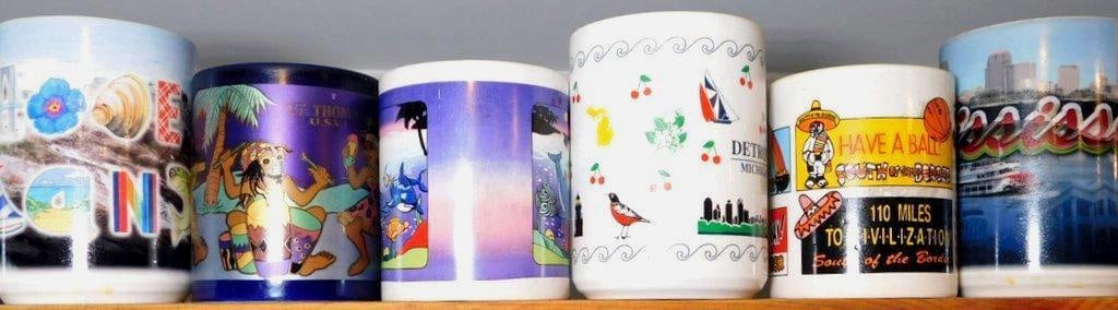 Six Assorted Ceramic Souvenir Mugs: Six ceramic souvenir mugs featuring diverse designs and themes Each mug presents colorful imagery, including landscapes, animals, cultural scenes, cityscapes, and text They appear to come from