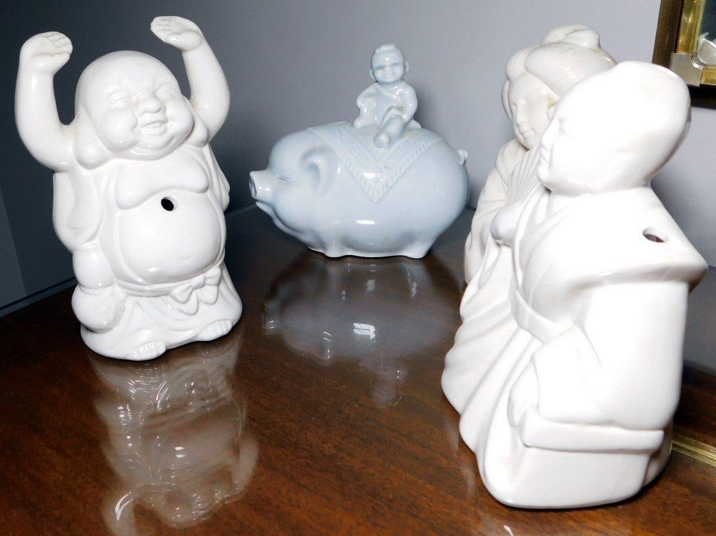 Four White Ceramic Figurines, Chinese Design: White ceramic figurines including a Laughing Buddha, a piggy bank featuring a child rider, and a pair of traditional figures holding fans Stamped Made in China on the bases with some wear and minor