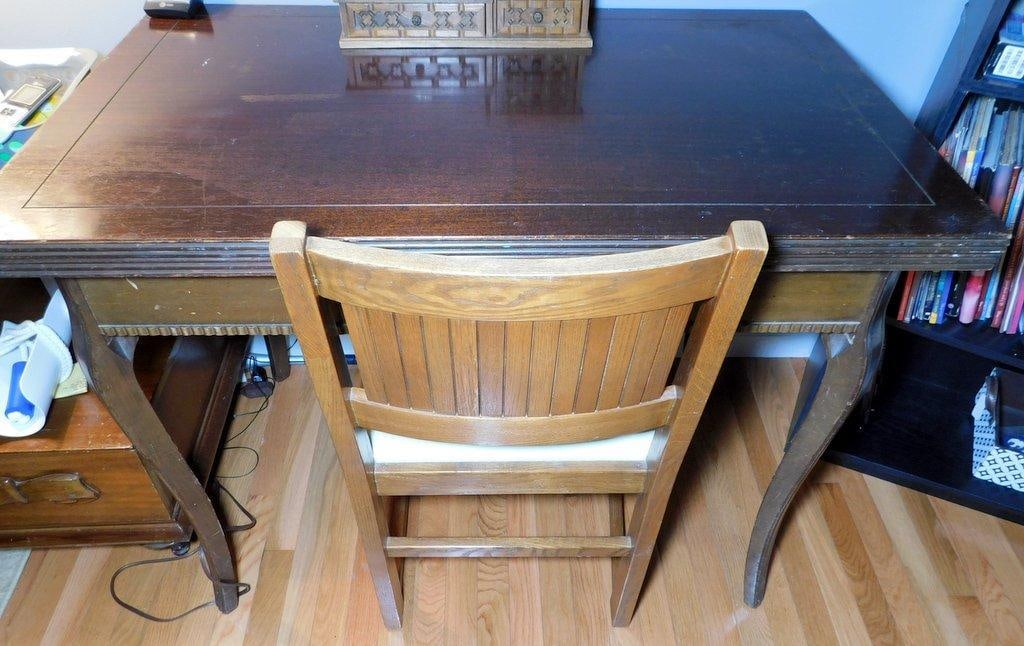 Wooden Desk w/ Decorative Chair and Desk Organizer: Wooden desk with a large top surface and decorative carved details, accompanied by a wooden chair with an upholstered seat The desk shows signs of wear and surface scratches A carved wooden desk