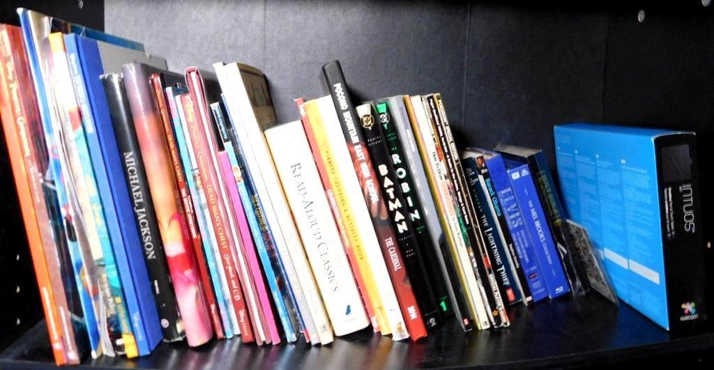 DVDs, Books, and Blu-rays Featuring Disney, Literature, and Music: A diverse collection of DVDs, books, and Blu-rays including Disney DVDs like Monsters University, High School Musical, and Santa Clause 2, along with works such as The Lightning Thief, 'The Mel