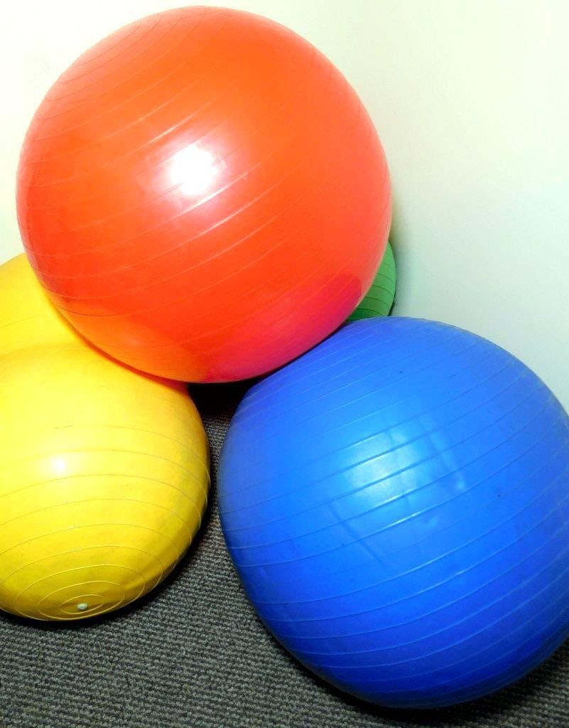 Colorful Physio Balls, Physio-Roll, and Accessories: Exercise equipment including colorful physio balls (red, blue, green, and yellow) and a yellow Physio-Roll ball by Sportime, made in Italy Includes a yellow air pump with blue and red attachments,