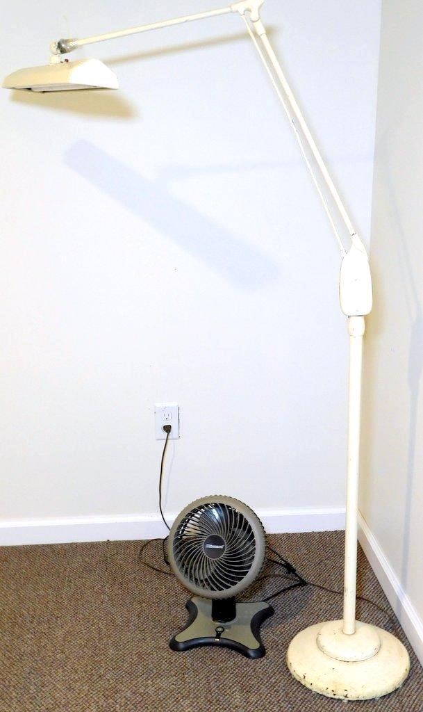 Adjustable Floor Lamp and Blizzard Fan Set: A white adjustable floor lamp and a Blizzard brand tabletop fan The lamp has a weighted base and adjustable arms Notable wear includes tape and zip tie repairs on the lamp's arm and surface scratches