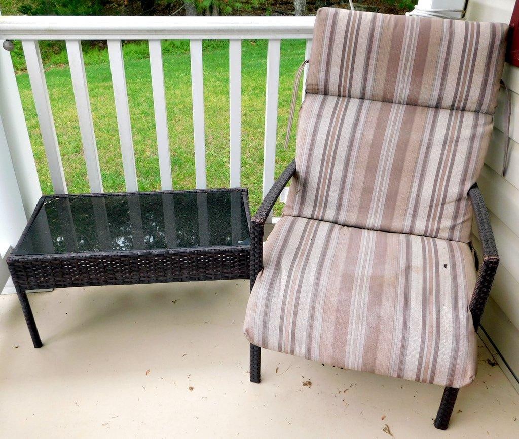 Outdoor Wicker Patio Chair and Glass-Top Table Set: Outdoor furniture set includes a wicker patio chair with a striped cushioned seat and a glass-top wicker rectangular table The chair features armrests with matching wicker detailing and a high backres
