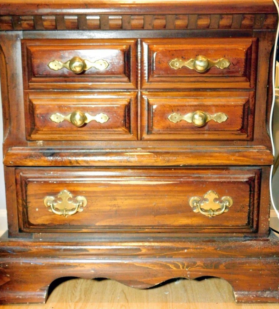 Pair of Wooden Nightstands: Wooden nightstands Each is crafted from stained wood with visible grain patterns and decorative brass hardware on the drawers Batwing brass pulls on each drawer Includes an ornate veneer design on