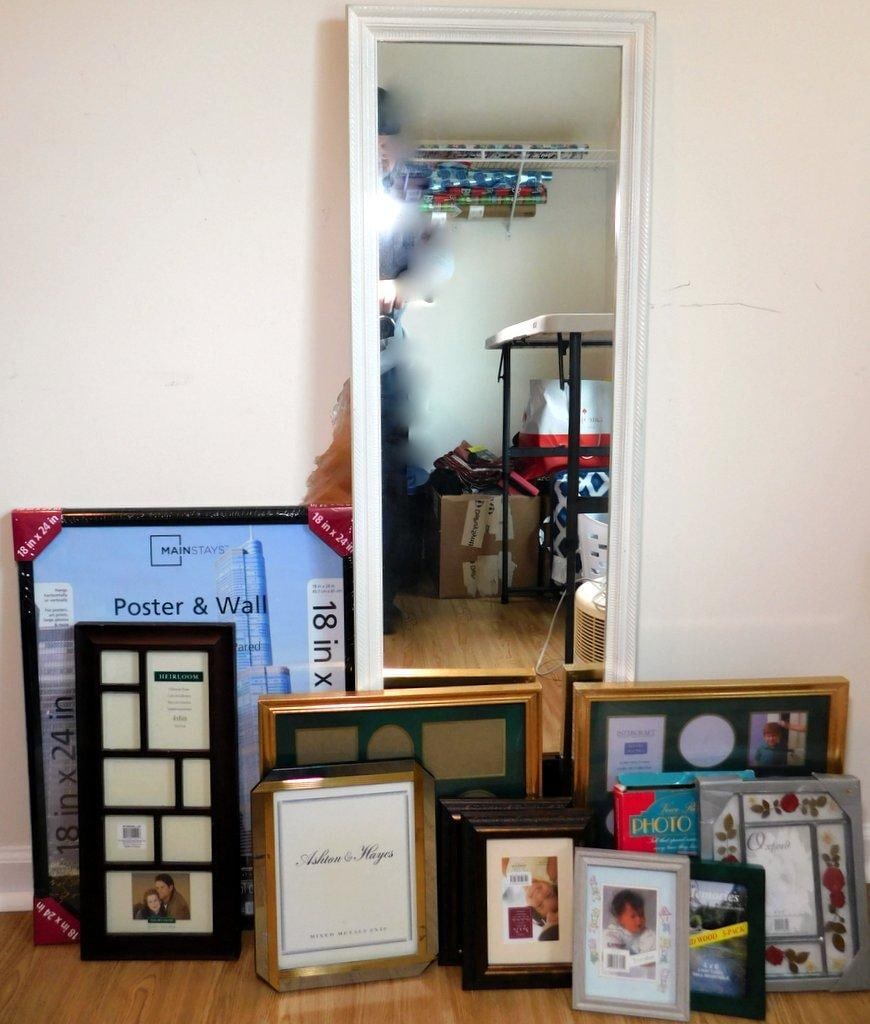 Mirror and Assorted Photo Frames Grouping: One large floor-length mirror with a white frame and an assortment of photo frames in various sizes and designs Frames include new and unused units, such as a 18 x 24 poster frame by Mainstays,