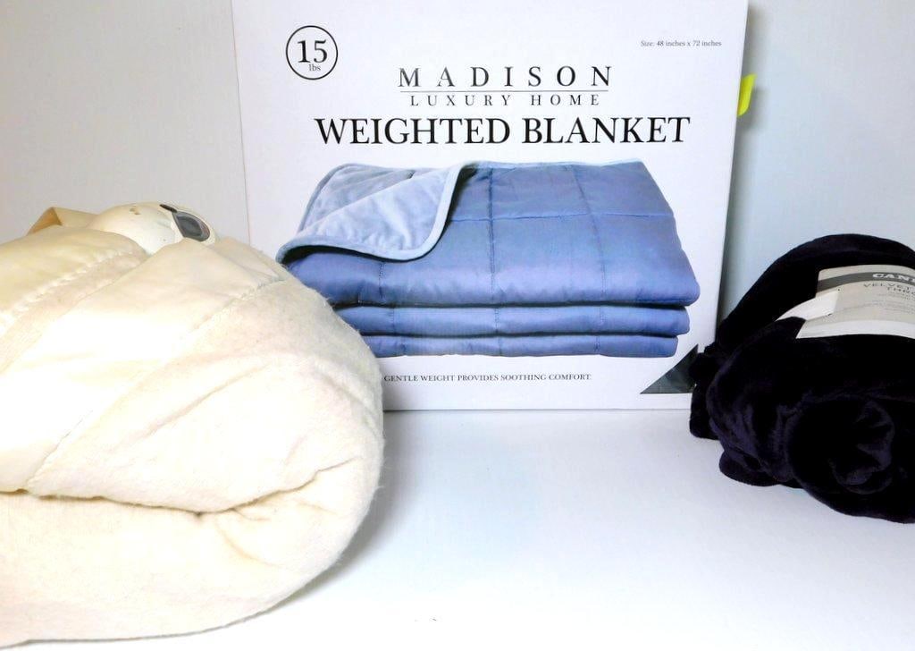 Weighted Blanket, Heated Blanket, Throws, and Massage Pads: Home goods lot including a Madison Luxury Home 15 lb weighted blanket, a Sunbeam heated blanket (model L78-DD2S), a Cannon Velvet Plush Throw (50 x 60 inches, 100% polyester), and two massage