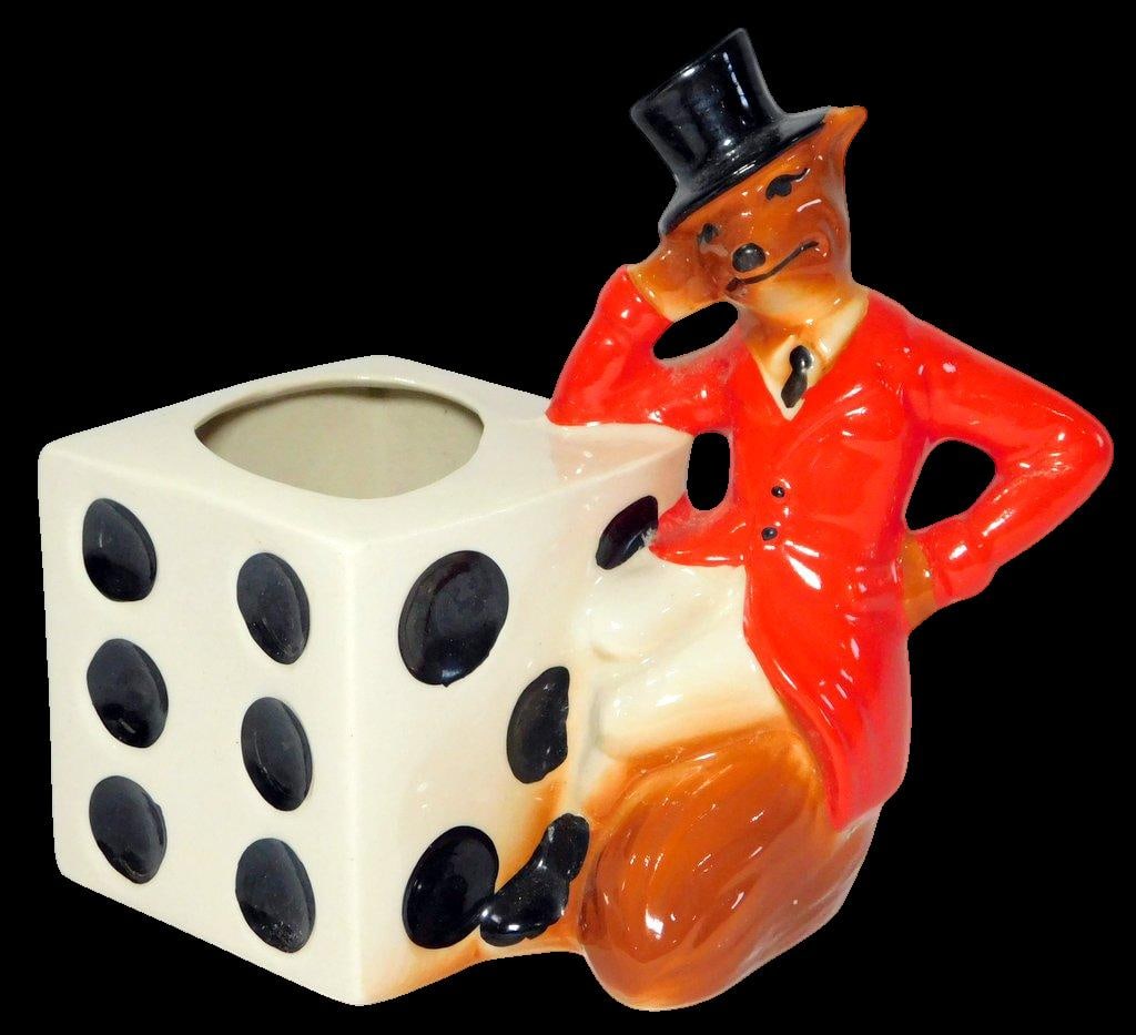 1981 IAJBBSC Annual Convention Ceramic Fox and Dice Figurine Straw Holder: Ceramic fox figurine in a red jacket and top hat leaning on a large die Inscription on the back reads I.A.J.B.B. & S.C., 11th Annual Convention, Las Vegas, Nevada, 1981 Marked underneath as