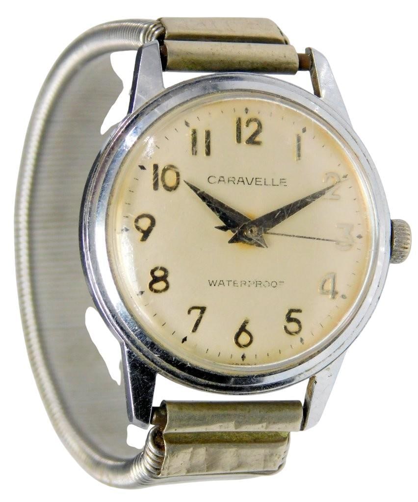 Caravelle Stainless Steel Waterproof Wristwatch: Caravelle wristwatch featuring a cream-colored dial with black Arabic numerals and a metal hour and minute hand Manual wind The case is noted as stainless steel with a waterproof, anti-magnetic