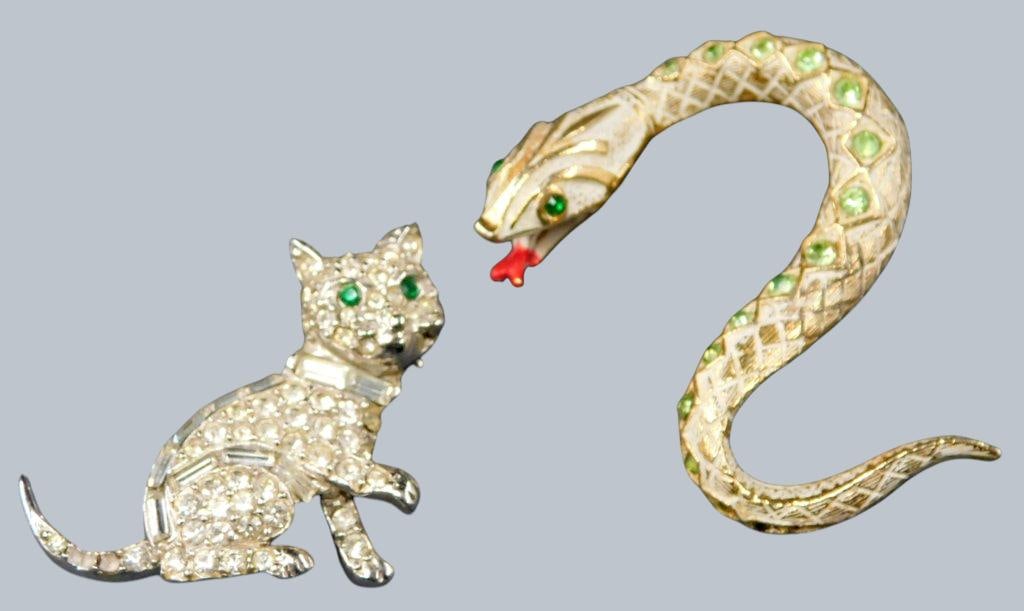 Art and Pell Designer Brooches Featuring Snake and Cat Designs: Designer brooches featuring a snake brooch by Art and a cat brooch by Pell The snake brooch is gold-tone, adorned with green rhinestones along the body and red enamel detailing on the tongue The cat