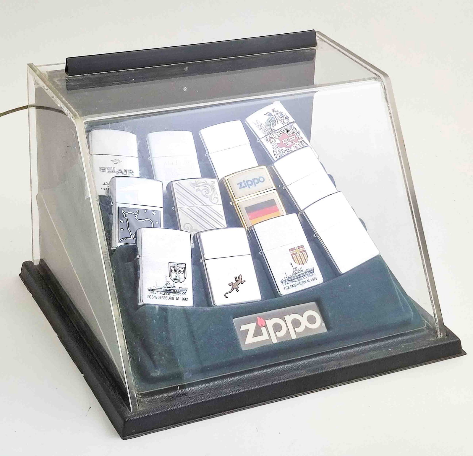 Zippo Feuerzeuge Aufsteller: Original Zippo Feuerzeuge in orig. Zippo Aufsteller, 12 Stk. versch. Modelle u.a. USA, Germany, Stierdekor, ziseliert, Funktion ungeprüft, aus großer Sammlungsauflösung Interne Nummer A0181400072