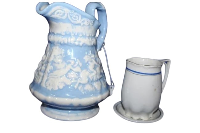 Lot of 2 Blue and White Ceramic Pitchers: 2 ceramic blue and white pitchers. One is small and comes on a tiny saucer, appears to have been part of a tea set at one time. The other is large, and appears to be hand thrown, hand painted, and dat