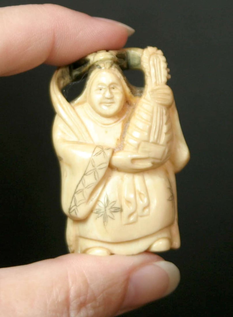 antique Asian carved bone Netsuke: vintage or antique Japanese Netsuke made of carved bone, great figural piece depicting a full body person playing a musical instrument (Lute?), with nice black details and signed by the ar