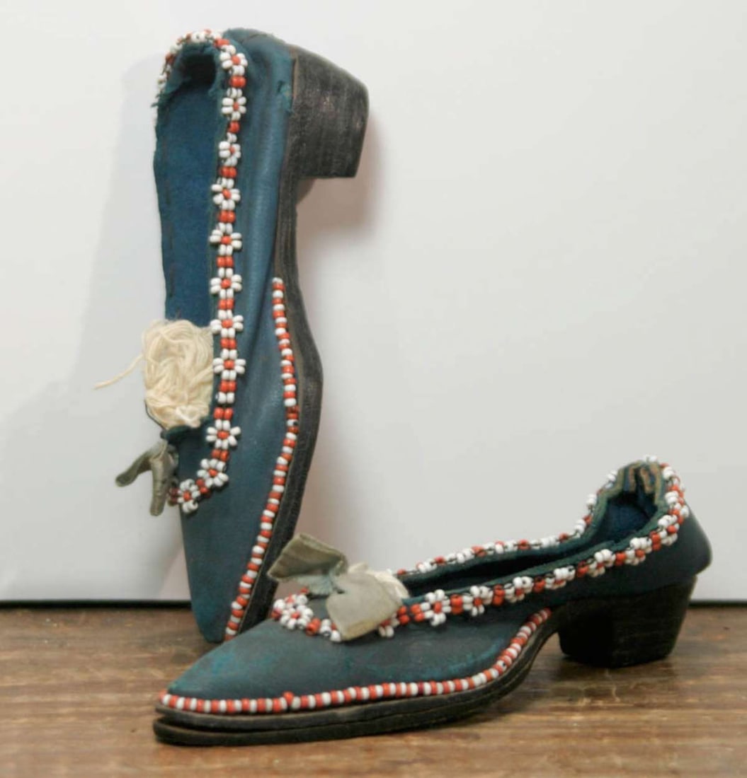 antique miniature pair of shoes: pair of antique leather soled and blue fabric miniature ladies' shoes with tiny seed bead hand stitched floral or flower design and bow, tip of toe stuffed.......not sure if these were made