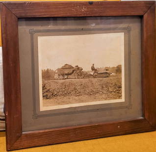 antique framed cabinet photo Black Americana: simple oak wooden frame with matted sepia toned antique photograph depicting a Black or African American teenage boy riding a sort of farm tractor and pulling a wooden cart with dirt&comma; the tracto
