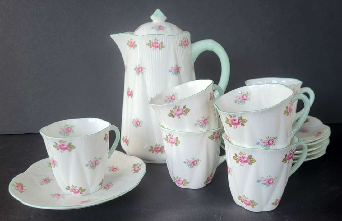 vintage English Shelley Rosebud tea set: English bone chine tea set, marked as shown Shelley England and consisting of 6 demitasse handled cups and saucers and a lidded teapot, all with delicate pink floral or flower design