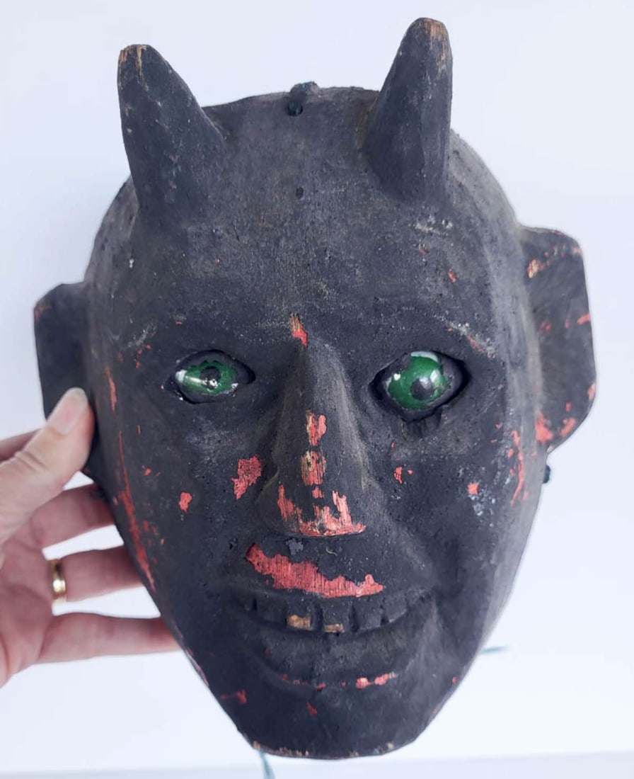 vintage Mexican Folk Art Devil mask: vintage carved wooden mask with black over red paint and green glass eyes, depicting a Devil or evil being with teeth barded and horns on his headInfo from online search: "The symbolism ref