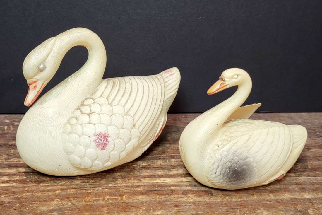 PAIR antique celluloid rattle bird toys: set or lot of two graduating sized similar style celluloid vintage or antique swan shaped toys, white with black and yellow accent colors, smaller with protruding wings and the larger one