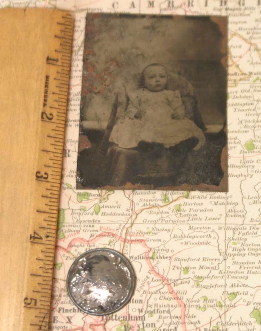 pair antique tintype photographs: first a mounted in metal frame (for use as a jewelry pendant?) portrait photograph of a young man, the second a black and white tintype of a toddler (girl or boy) in a white dress, sitting