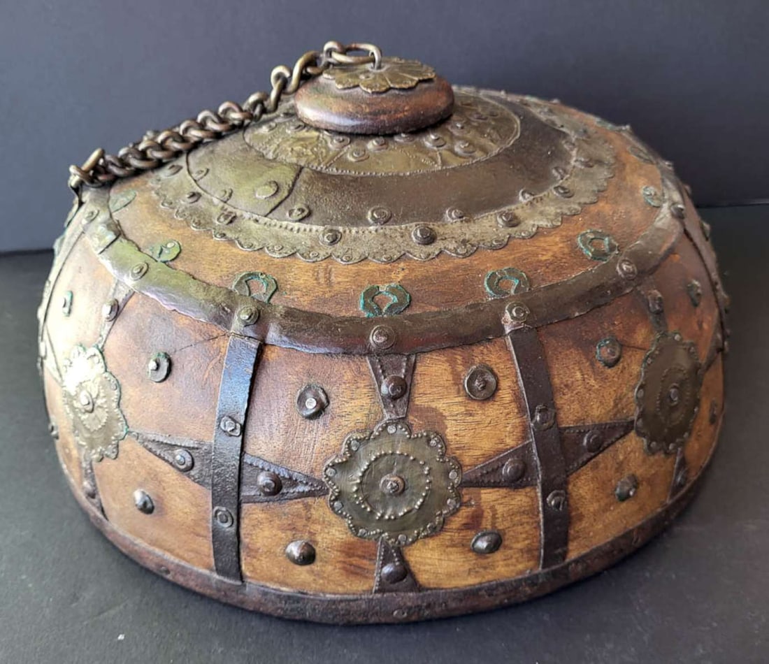 antique tobacco or opium box: antique wooden with hand forged and hammered metal overlay strap and floral or abstract flower design wooden box with lid or stopper on a chain, not sure if this is African or Middle Eastern (?)