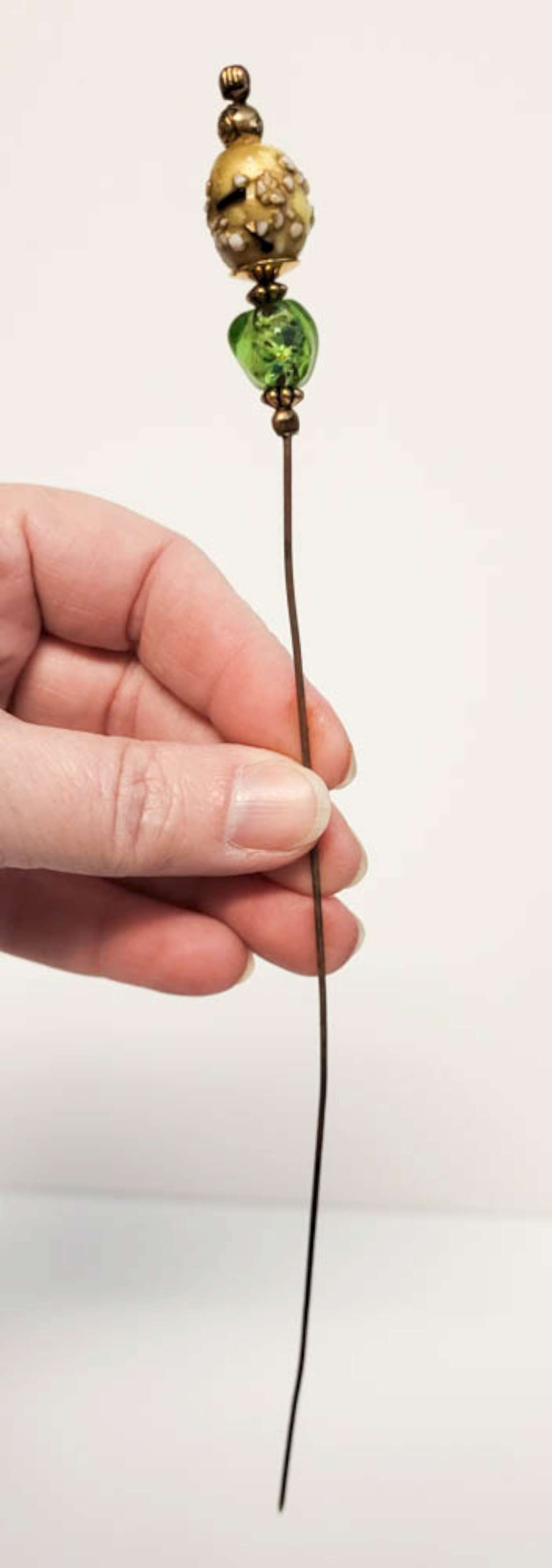 vintage hat pin unusual glass beads: vintage or antique long hat pin with metal post, gold toned (untested, possibly gold?) parts and green and yellow and white bumpy glass beads