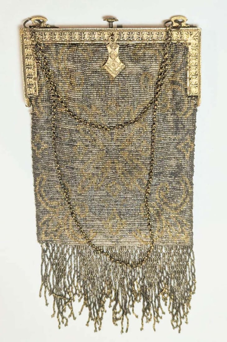 Art Deco period handbag or purse: vintage or antique, ca. 1920's micro-beaded bag with a chain holder, gilt finish push closure with abstract floral or flower design and fringe on the bottom, gold and silver ton