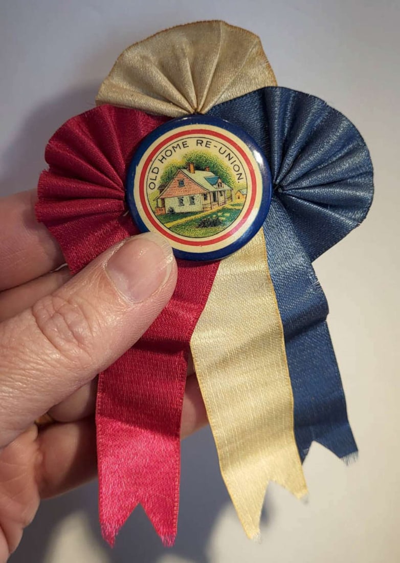 rare antique Re-Union button on ribbon: vibrantly colored antique celluloid pin or button Old Home Re-Union on an intricately folded red, white and blue ribboninfo from online search: "Old Home Re-Union, a tradition similar