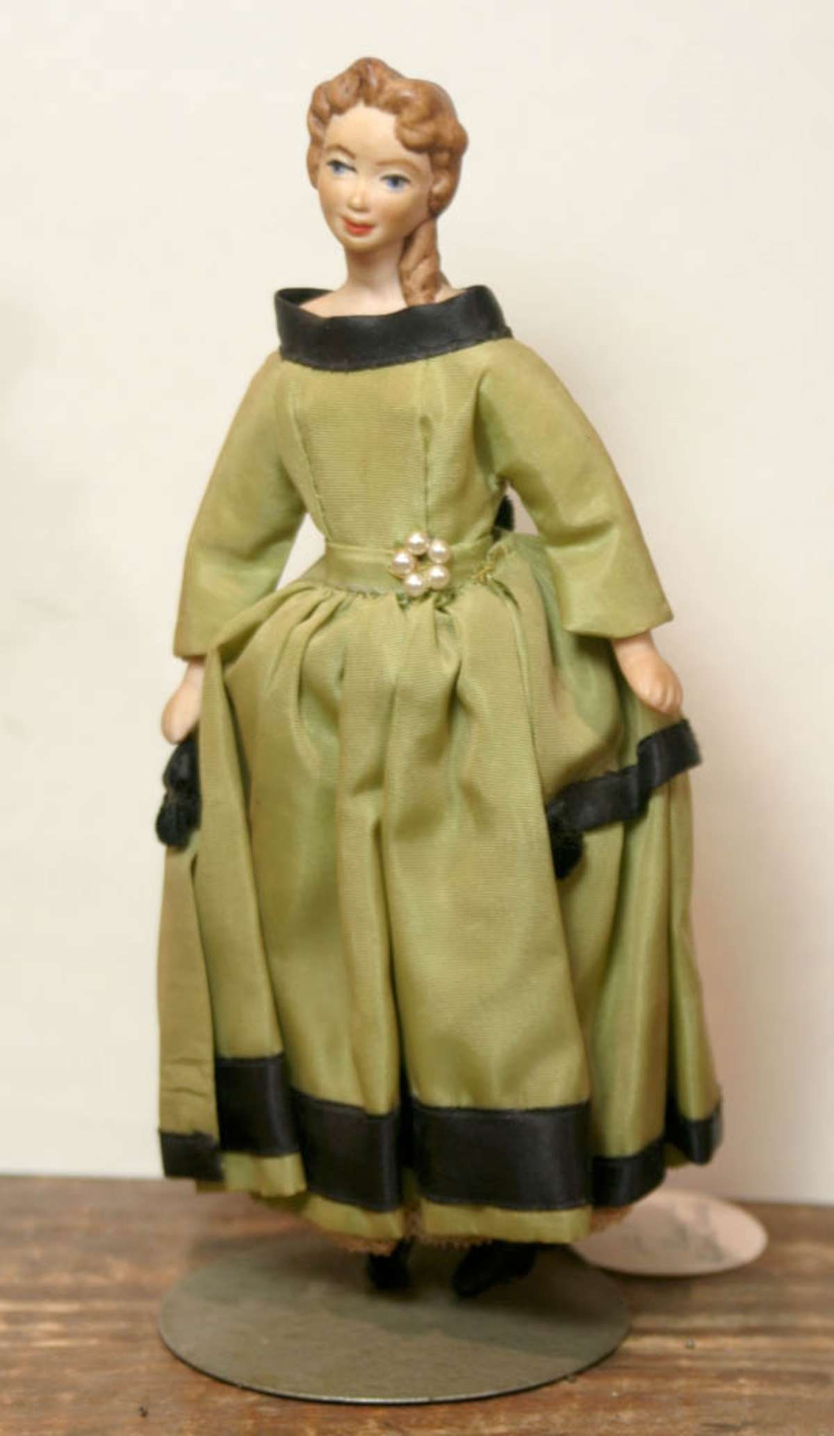 vintage small porcelain lady doll: possibly a Little Women doll with bisque or porcelain hard and shoulders, arms and legs and beautiful green dress with black trim, unmarked