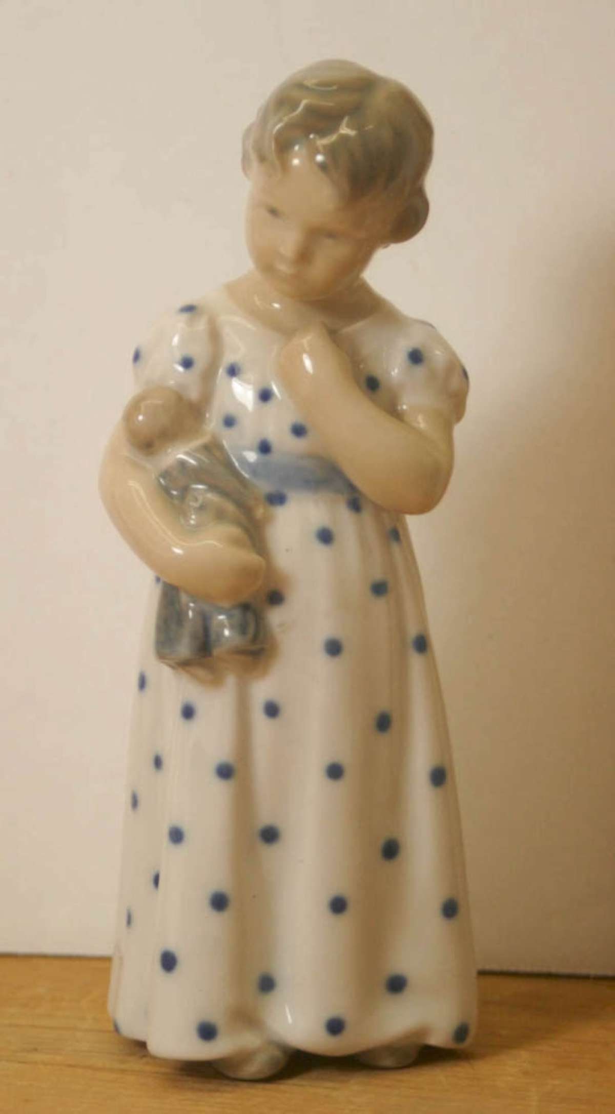 vintage Royal Copenhagen porcelain figural statue: vintage Danish porcelain figural statue of a young girl in a white and blue polka dotted dress holding her doll, marked crown logo Denmark, waves mark and numbered 3539 as shown