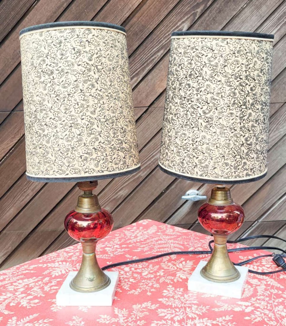 pair antique Cranberry glass table lamps: this is a matching pair of antique brass oil lamps (converted to electric) lamps with cranberry colored blown glass bodies and set on a white stone (marble?) base, with vintage clip-on (see clos
