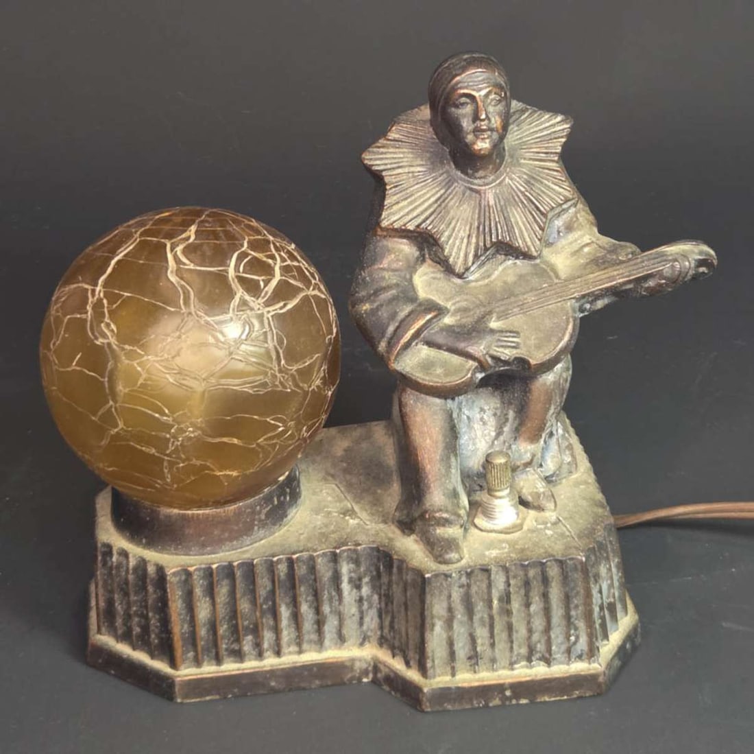 antique Art Deco harlequin table lamp: vintage or antique Art Deco period boudoir lamp shaped like a clown or harlequin playing a guitar or other musical string instrument and with an original period crackled glass yellow or Amber colored 