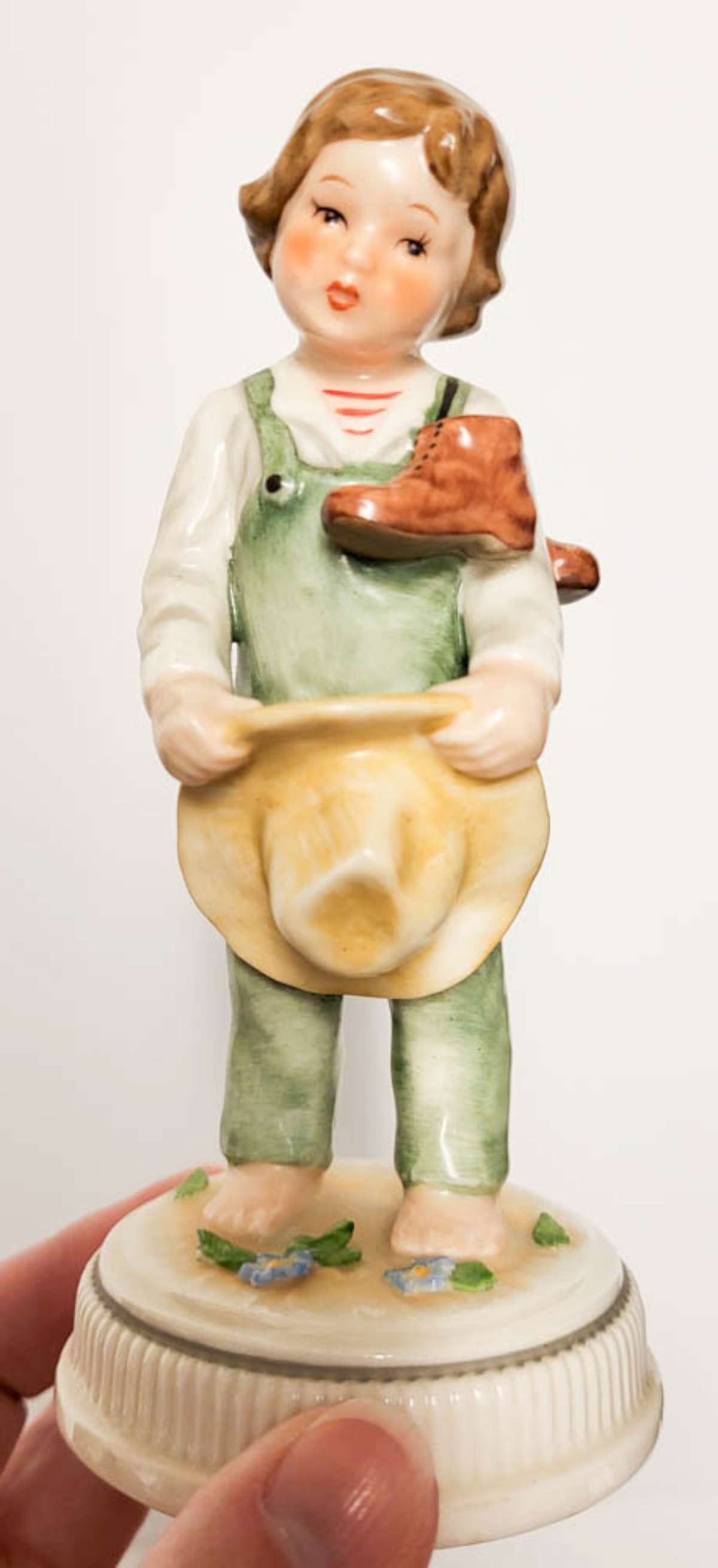 adorable Hummel boy statue by Goebel: vintage marked Lore Goebel Germany numbered 229 as shown figural Hummel figurine titled Blumenkinder, shaped like a boy in green overalls holding his hat in his hands